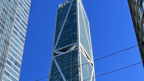 181 Fremont’s white-braced glass tower against a deep blue sky, with a neighboring shaft at left and a cable across the frame. No people appear.