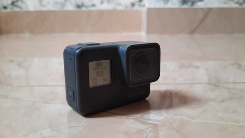A GoPro HERO action camera on a tiled floor showing 1080 60 W on its front screen. No people appear.