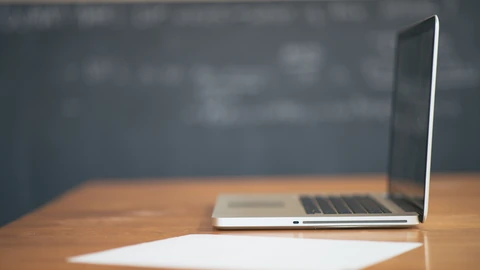 Open laptop on a desk with papers and a coffee cup nearby. No people appear.
