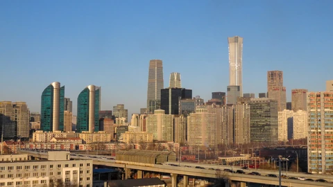 Beijing’s CBD skyline under a clear winter sky, with an elevated roadway in the foreground. Distant vehicles appear as unreadable specks. No identifiable people appear.