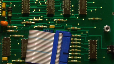 Vertical close-up of a circuit board with dense surface-mount components. No people appear.