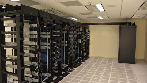 Rows of black server racks with blue LED indicators in a data-center aisle. No people appear.