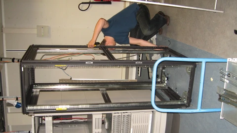 Two tall empty server racks with open rails in a machine room. No people appear.