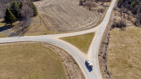 An empty paved road splitting into two directions under a blue sky. No people appear.