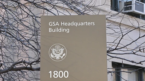 Stone and metal General Services Administration headquarters sign at street level. No people appear.