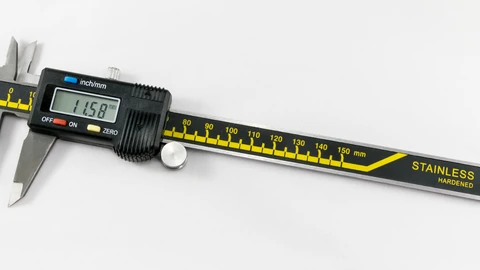 Digital caliper resting on a wooden surface showing a measurement readout. No people appear.