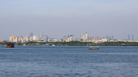 West Lake water in the foreground with Hangzhou high-rises on the far shore under a pale sky. No people appear.