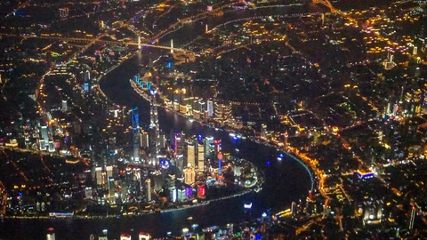 Night aerial of Shanghai’s Lujiazui peninsula, with the Huangpu River bending around illuminated towers. No people appear.