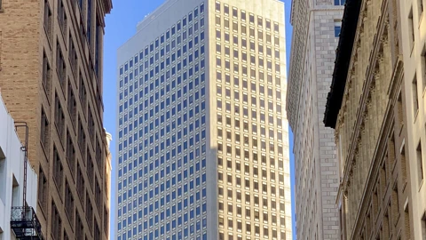 The upper shaft of Market Center, a pale office tower with a regular grid of windows, framed by two neighboring facades against a clear blue sky. No people appear.