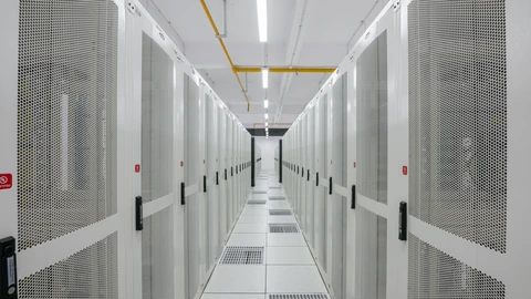 Rows of illuminated server racks in a data-center hall. No people appear.