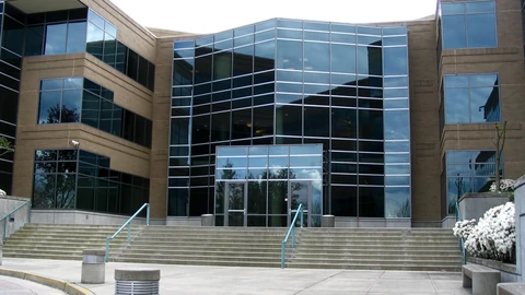 Empty glass lobby entrance and brick facade of Microsoft Building 17, with concrete bollards and no people.