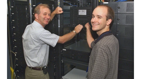 A dense server farm with blue LEDs and network cables. No people appear.