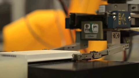 A white laboratory robot arm holding a translucent assay plate over a work deck. No people appear.