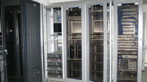 Five wheeled server racks with monitors and blue patch cables on a raised floor. No people appear.