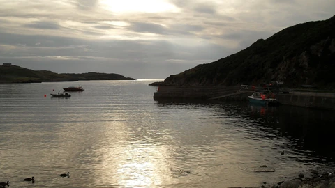 Evening light on Scourie Pier with calm water and distant hills. No people appear.