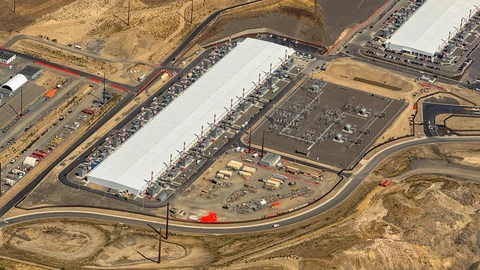 Aerial view of large white-roofed datacenter halls, an electrical substation and access roads on dry, brown land in Washington state.