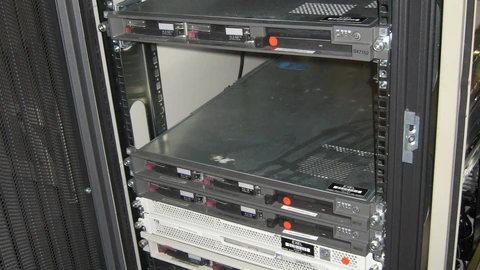 An open black 19-inch rack holding a few 1U servers and empty shelves, with loose cables on the floor. No people appear.