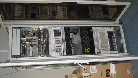 Network routers and switch racks with dense cabling in a server closet. No people appear.