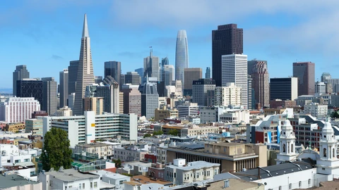 San Francisco downtown towers seen from a hillside park under a blue sky. No identifiable people appear.