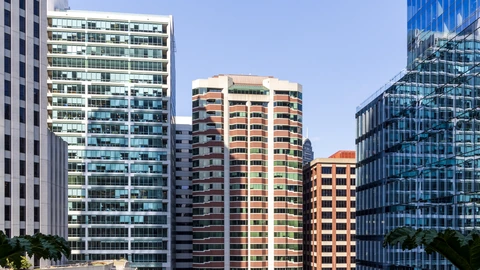Glass office towers northeast of Salesforce Park under a clear sky, with rooftop plantings in the foreground. No identifiable people appear.