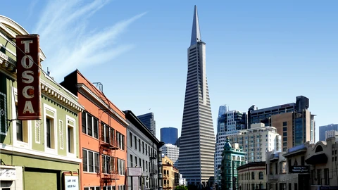 The Transamerica Pyramid rising above lower San Francisco rooftops under a clear blue sky. No people appear.