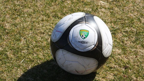 A black-and-white soccer ball resting on green grass. No people appear.