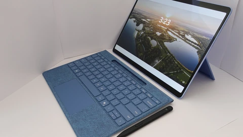 A blue 2-in-1 tablet computer with a detached fabric keyboard and black stylus on a white surface. No people appear.