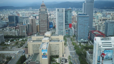 Dense Taipei rooftops and towers viewed from a high floor under haze. No identifiable people appear.