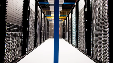 Close view of network and server hardware in a rack, with blue indicator lights. No people appear.