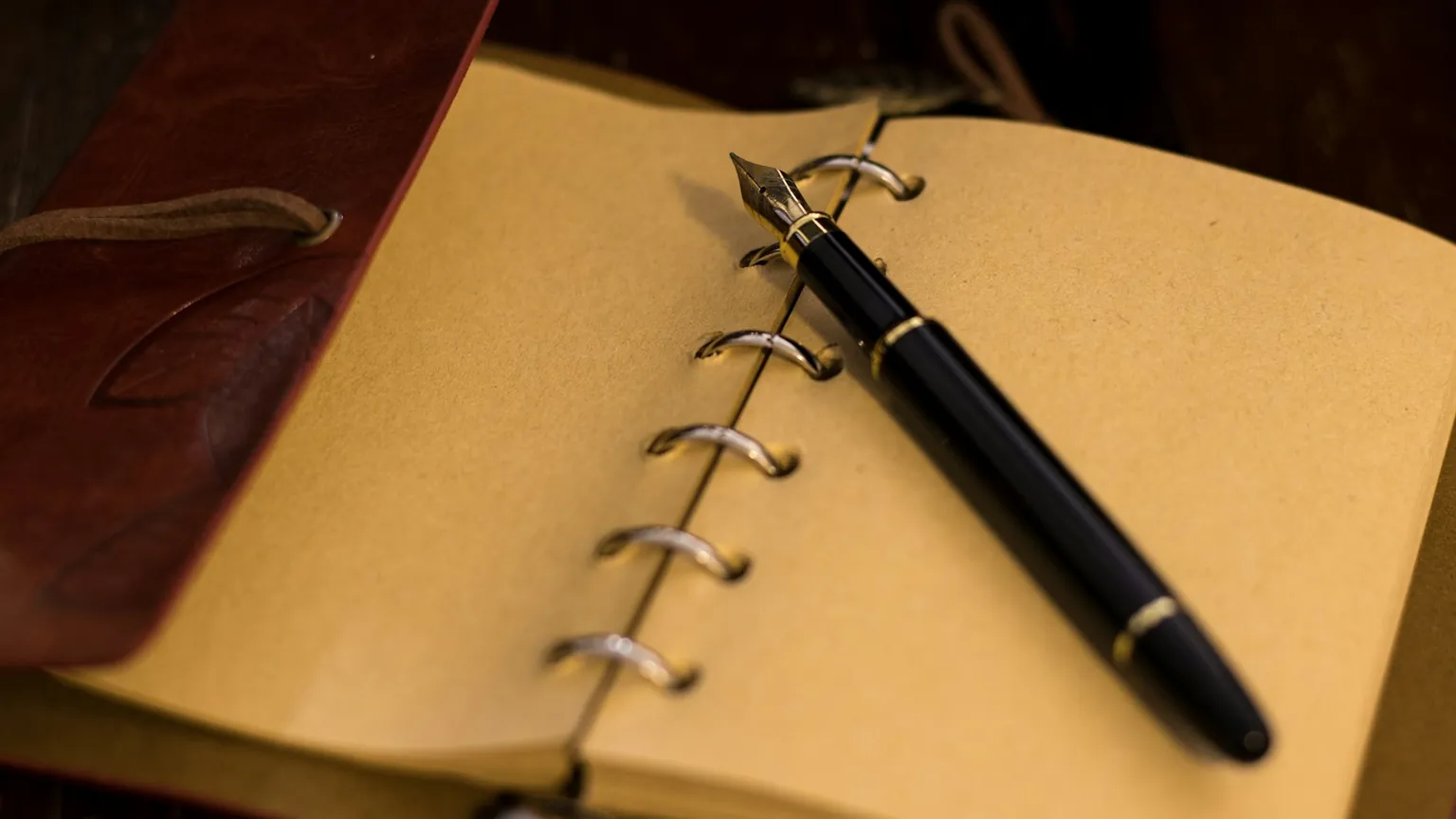 A fountain pen resting on a closed notebook.