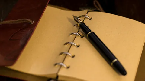 A fountain pen resting on a closed notebook.