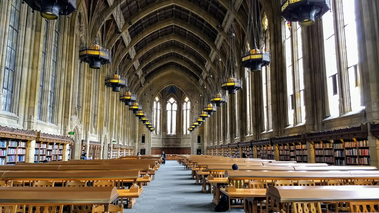 Long wooden tables and gothic windows in the Suzzallo Library reading room at the University of Washington.