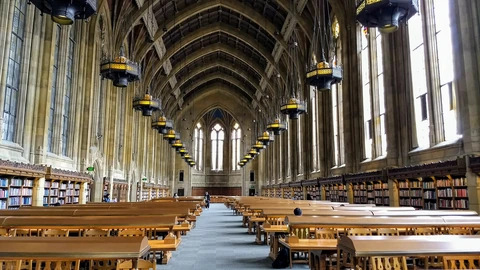 Long wooden tables and gothic windows in the Suzzallo Library reading room at the University of Washington.