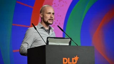 Aleph Alpha founder Jonas Andrulis speaking at a DLD-branded lectern in front of a colorful stage screen.