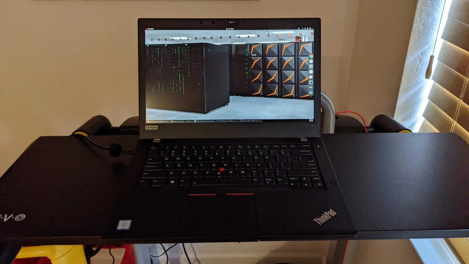 An open Lenovo ThinkPad T480 on a black stand, showing a photograph of server racks on the screen.
