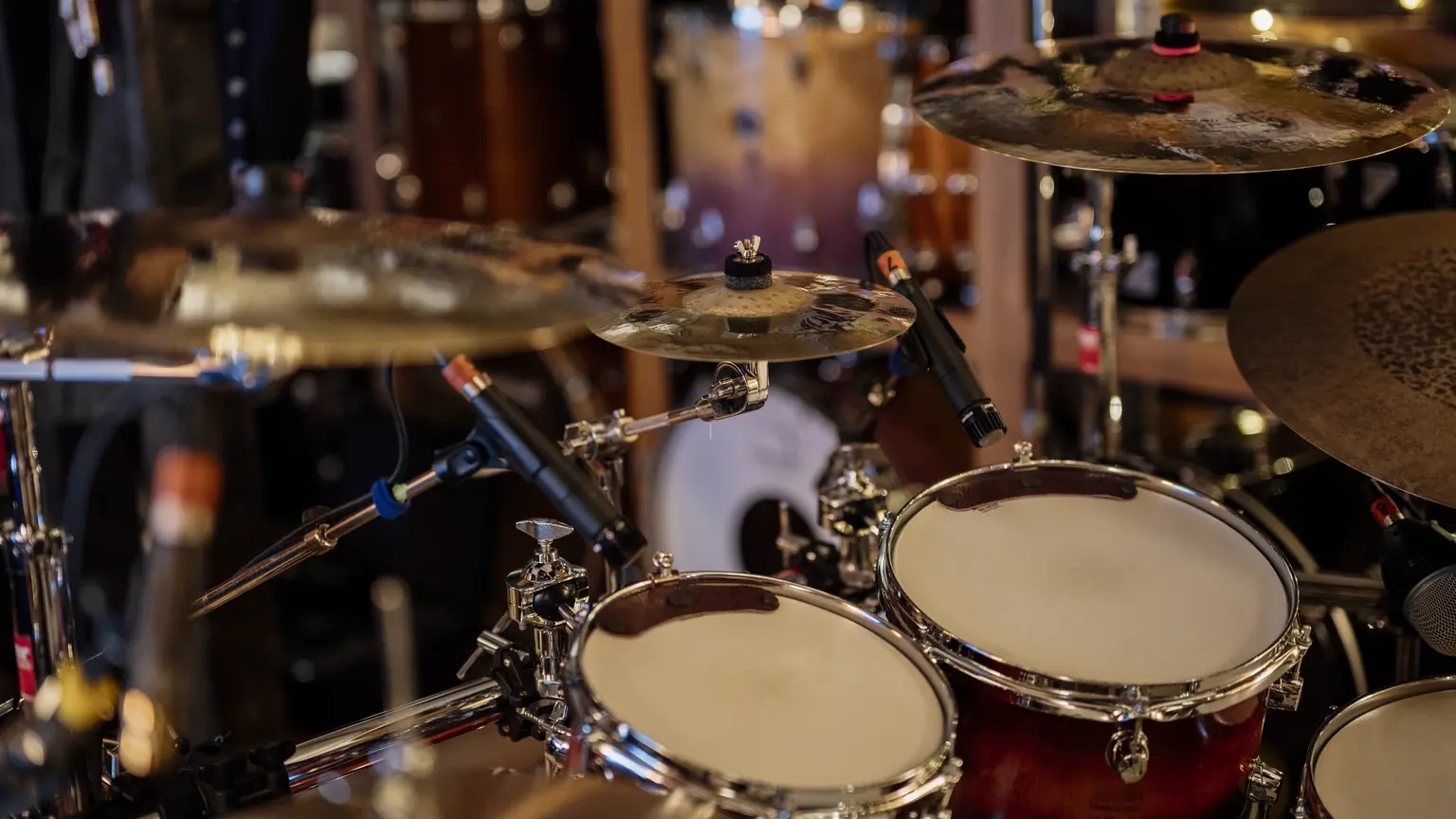 A drum kit surrounded by microphones in a recording studio.