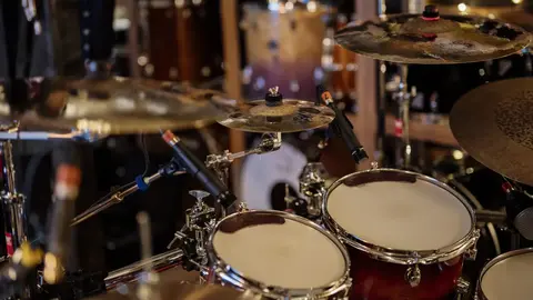 A drum kit surrounded by microphones in a recording studio.
