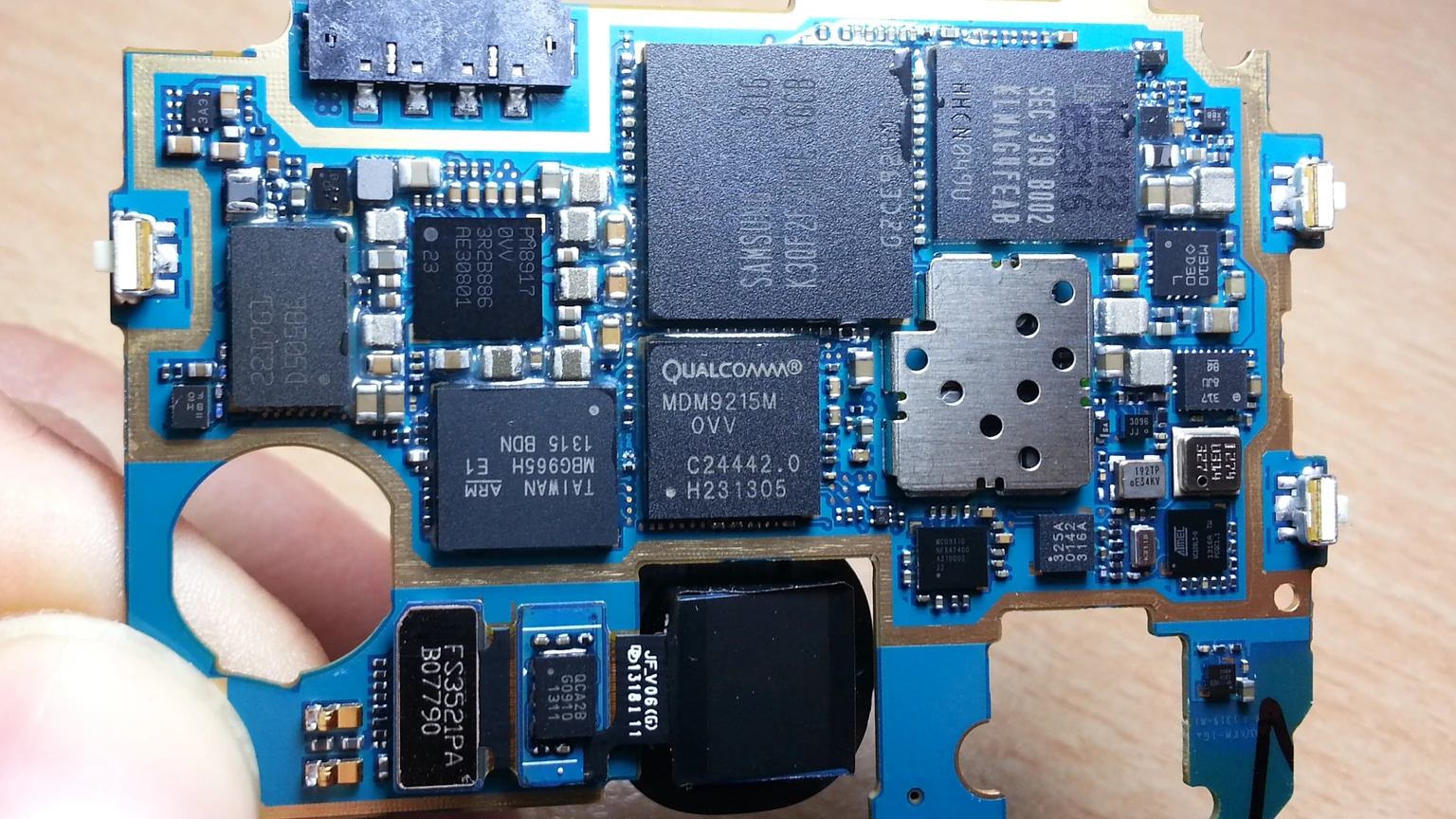 Close-up of the blue circuit board and chips inside a Samsung Galaxy S4 smartphone.