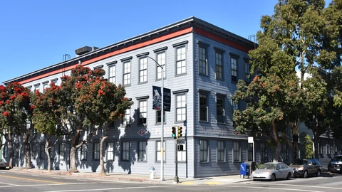 The grey Pioneer Building on a San Francisco street corner, with PIONEER BUILDING lettered on the facade and trees along the sidewalk.