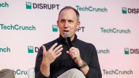 Sierra co-founder Bret Taylor holding a microphone and gesturing while speaking on a TechCrunch Disrupt stage.