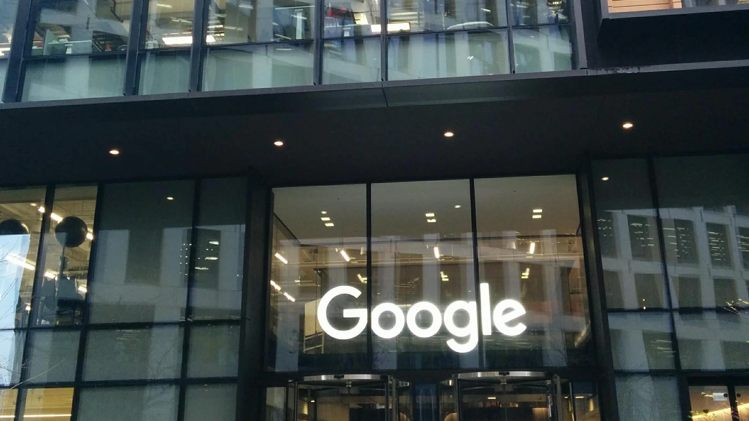 The glass entrance of a Google office at 6 Pancras Square in London, with a white Google logo above revolving doors.