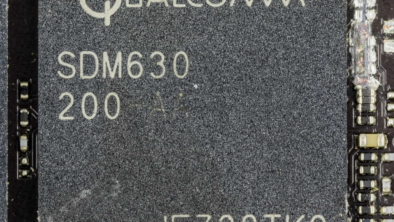 Close-up of a black Qualcomm SDM630 200-AA package on a phone board, with white part markings and no people in the frame.