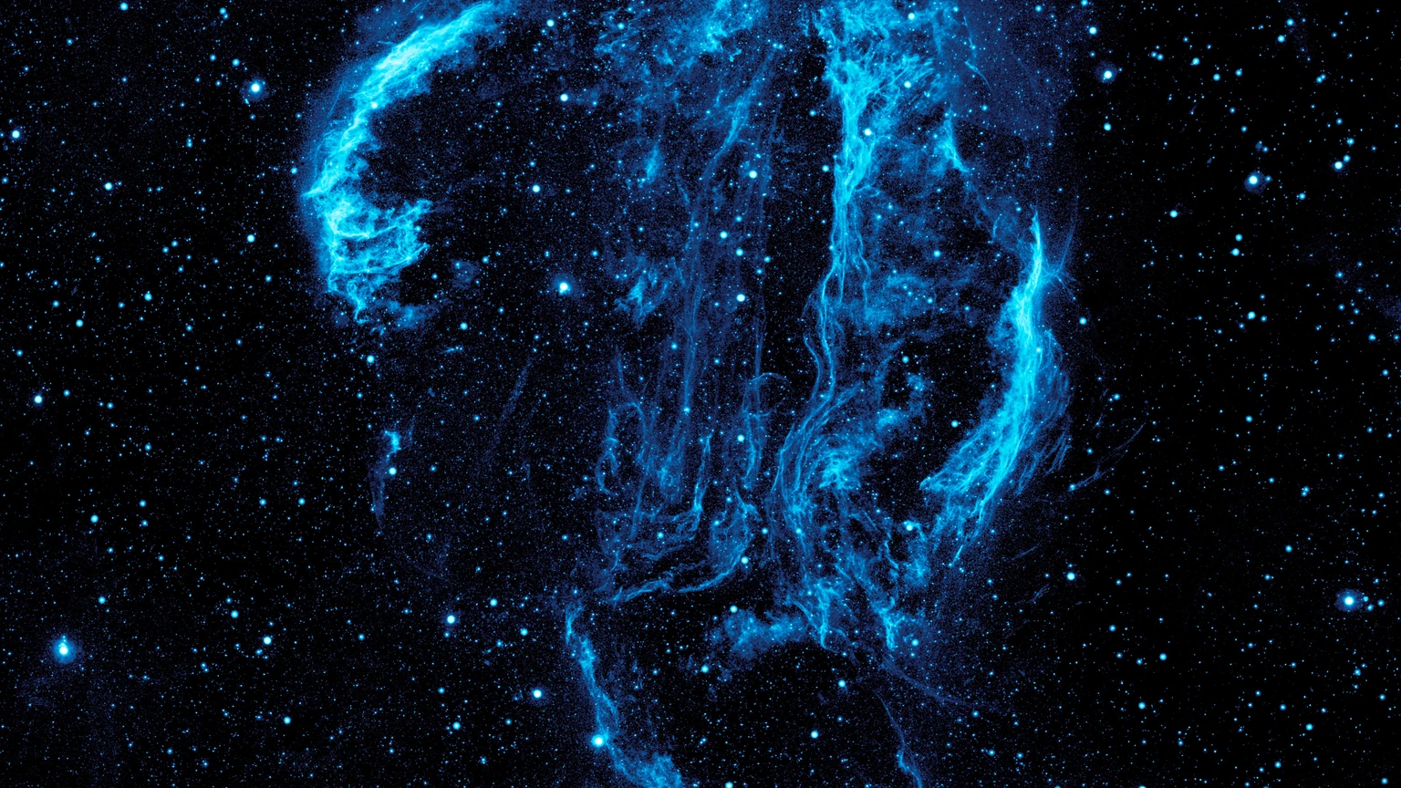 Wispy blue ultraviolet filaments of the Cygnus Loop supernova remnant against a star field, from NASA’s Galaxy Evolution Explorer.