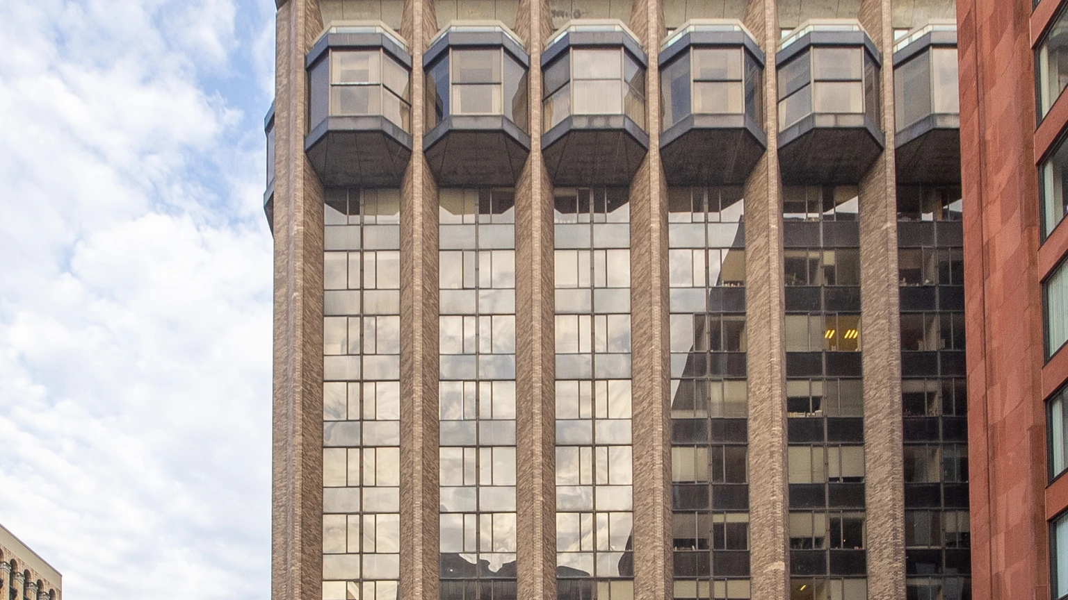 Warren Weaver Hall at NYU’s Courant Institute with a concrete facade and plaza trees. Distant pedestrians may appear small; none are identifiable subjects of this story.