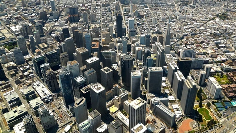 Aerial view of downtown San Francisco high-rises under a clear sky. No identifiable people appear.