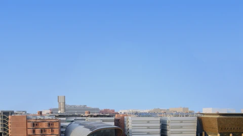 MBZUAI Knowledge Center and surrounding Masdar City campus buildings around a circular lawn and palm trees under a clear sky. Distant pedestrians may appear tiny on walkways; none are identifiable subjects of this story.