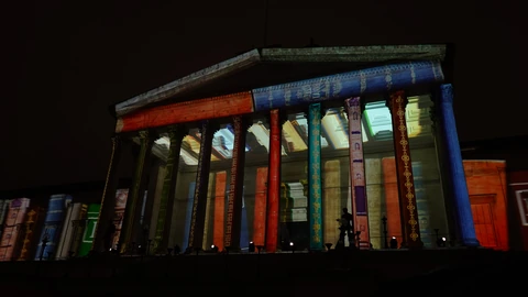 University College London’s Wilkins Building portico lit at dusk, with columns and a pale evening sky. No identifiable people appear.