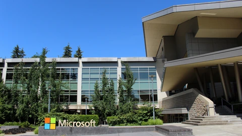Glass facade of Microsoft Building 92 on the Redmond campus under a clear sky. No identifiable people appear.