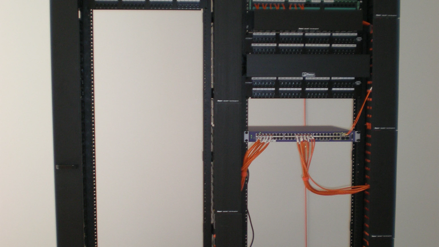 A tall network rack filled with patch panels and dense colored cables. No people appear.