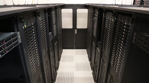 Rows of server racks with blue lighting in a data center aisle. No people appear.